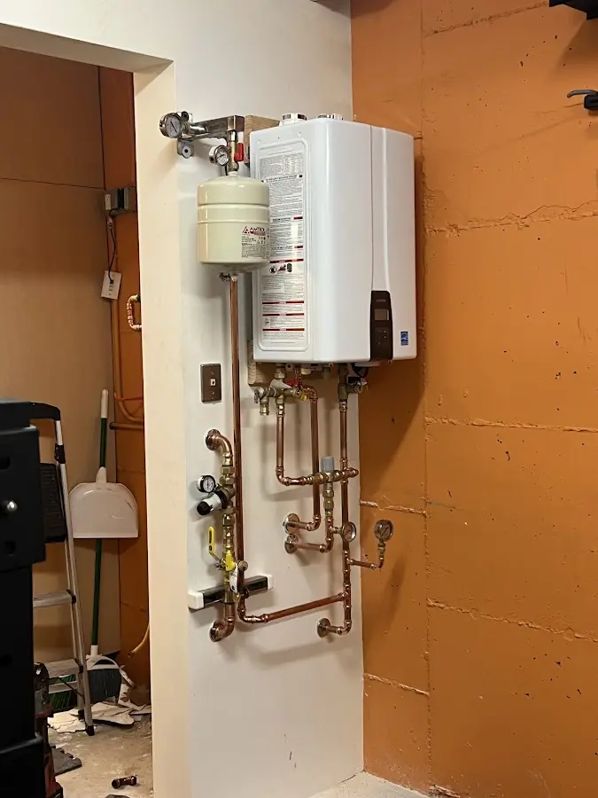 Plumbing technician inspecting water heater connections in Clyde
